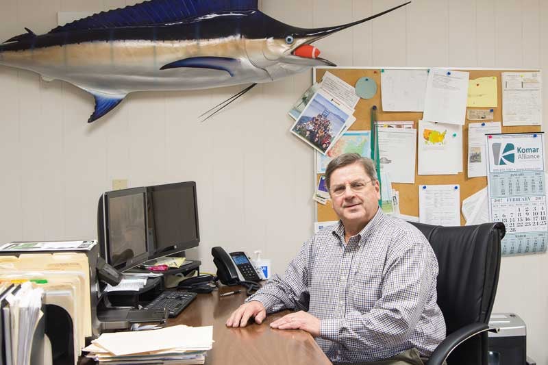 man at desk with fish on the wall smiling 
